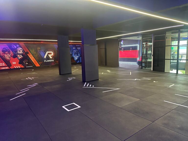 Interior do VR Parque com arena de movimento livre, áreas demarcadas e recepção